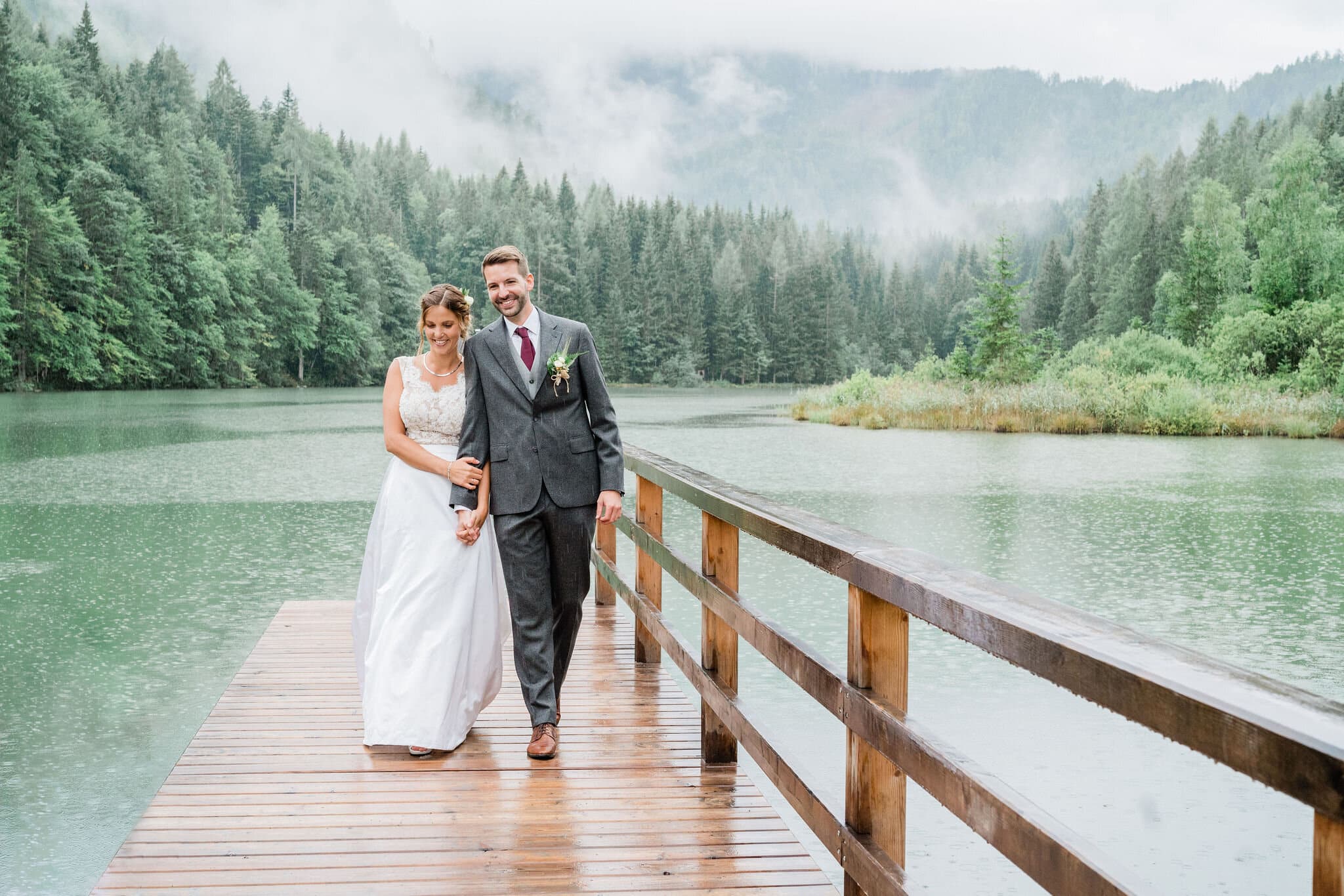 Brautpaar an ihrem Hochzeitstag am See im Regen