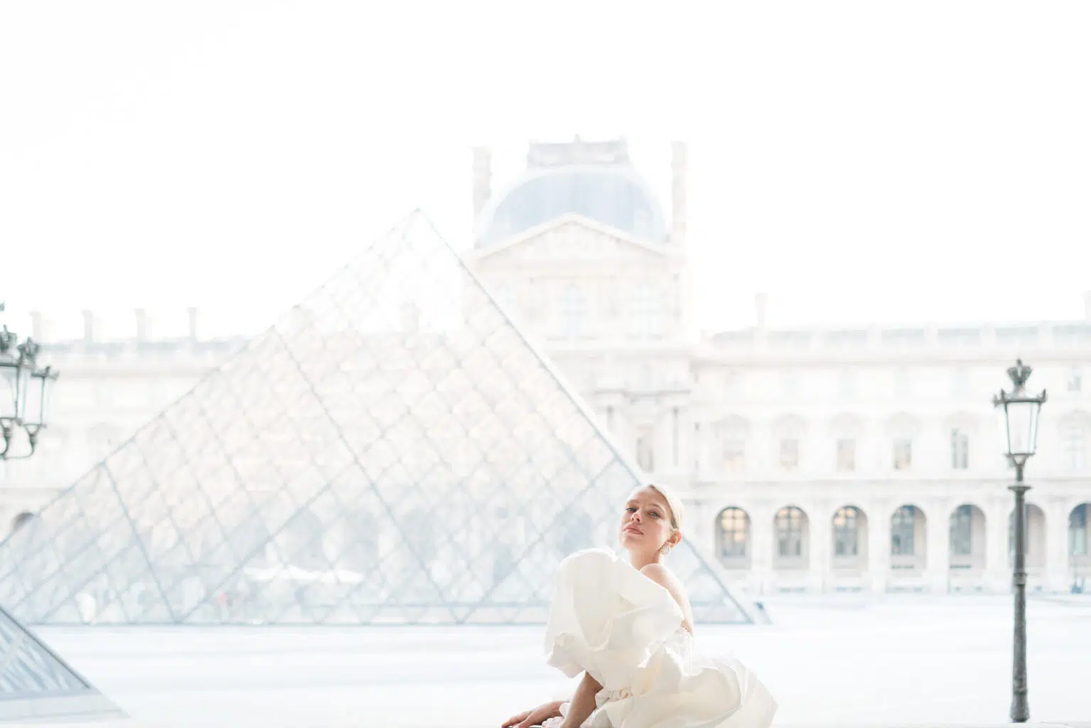 Braut posiert in einem luxeriösen Brautkleid vor dem Louvre in Frankreich